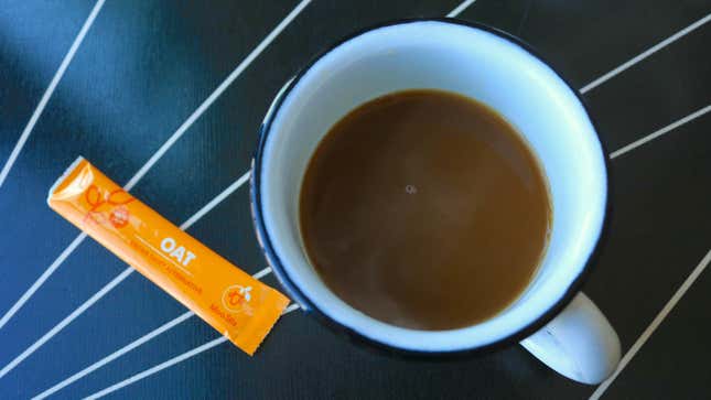 A cup of coffee with an empty Moo Stix satchet next to it.